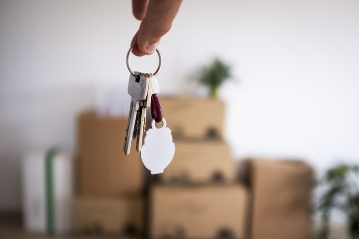 Close-up of the keys of the new empty apartment with moving boxes on the floor